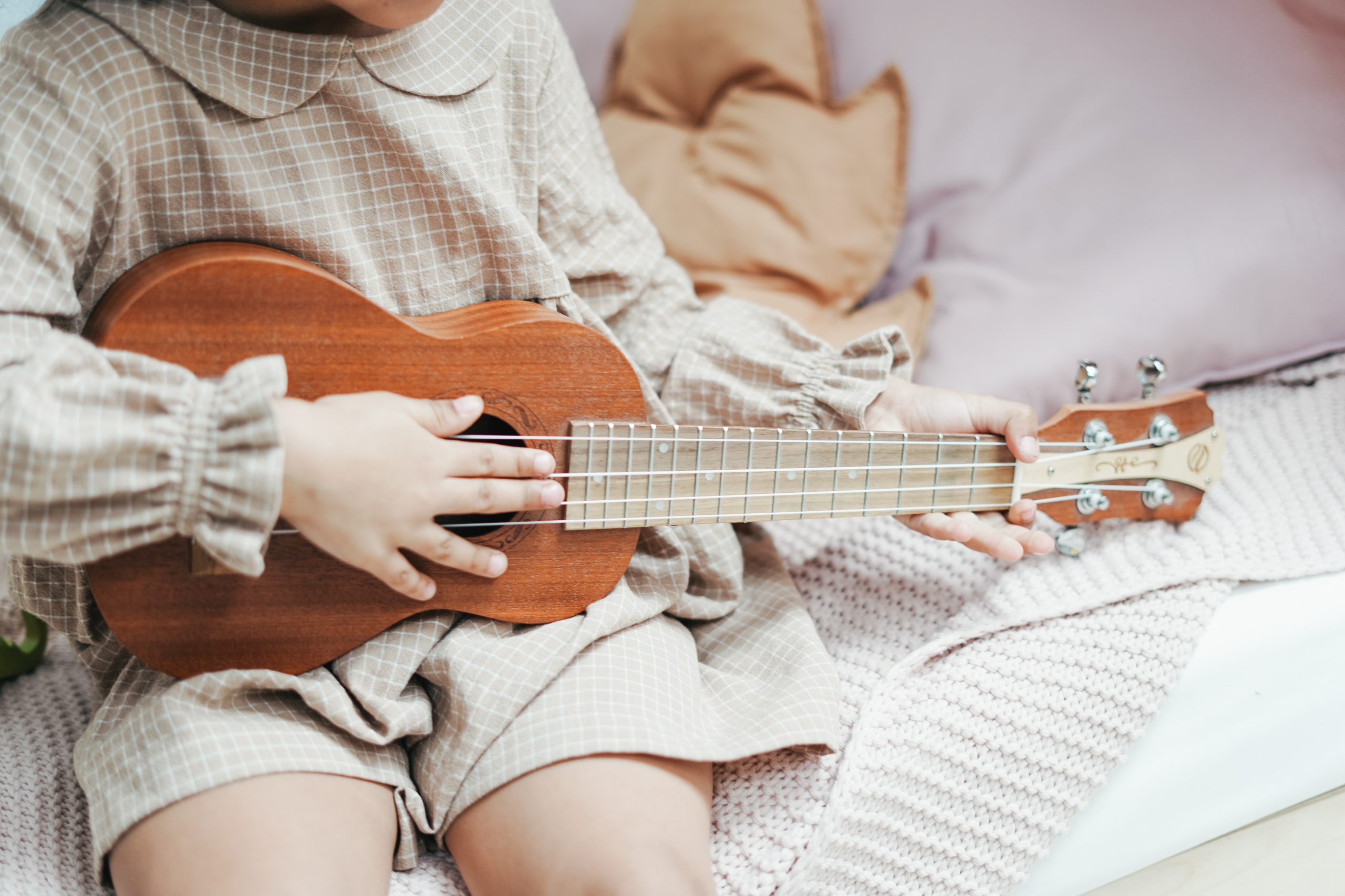 girl sitting on bed playing ukulele